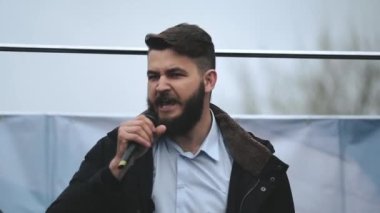 Sinirli sözcü mikrofonla sahnede konuşma ve isyan eylemciliği yapıyor..