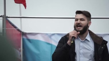 Mikrofonlu erkek spiker sahnede saldırganlığa hitap ediyor. İsyan eylemcisi sahnede..