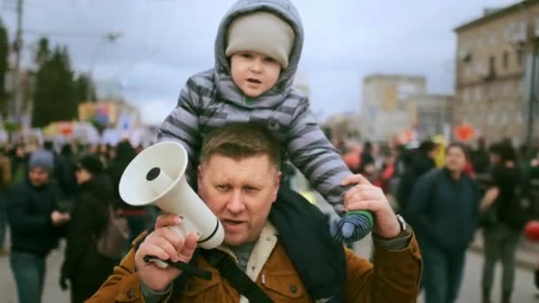 Father with sitting on shoulders kid. Parent with megaphone on political rally. — Stock Video