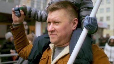 Bekar bir baba, erkek çocuğu omuzlarında yürür. Baba deneyimi, aile anıları