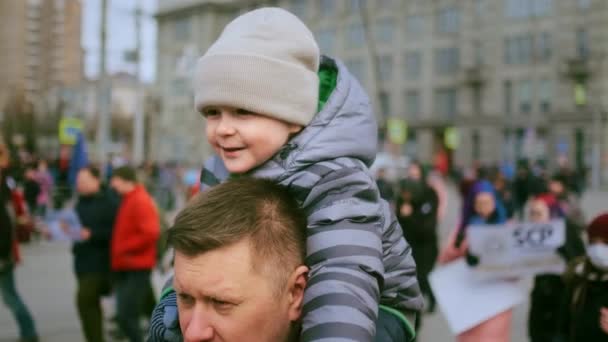 도시의 휴일 퍼레이드에서 가족의 행복 한 기억. 어린 아이가 아버지의 목에 앉아. — 비디오