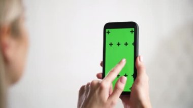 Kız iPhone 'u tutuyor ve kaydırıyor, yeşil renkli krom ekran..