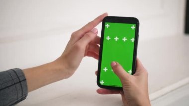 Kız iPhone 'u tutuyor ve kaydırıyor, yeşil renkli krom ekran..