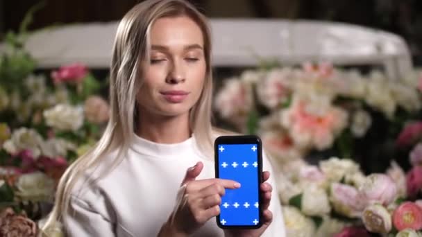 Porträtt av leende kvinna tittar på kameran med blå skärm telefon i händerna. — Stockvideo