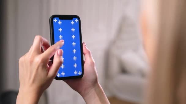 Woman slides, scrolls up and down blue chroma key screen in smartphone app. — Stock Video