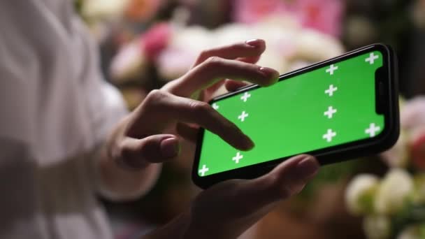 Κορίτσι κατέχει smartphone iphone στα χέρια με πράσινο mockup chroma οθόνη κλειδί για την αγγελία — Αρχείο Βίντεο