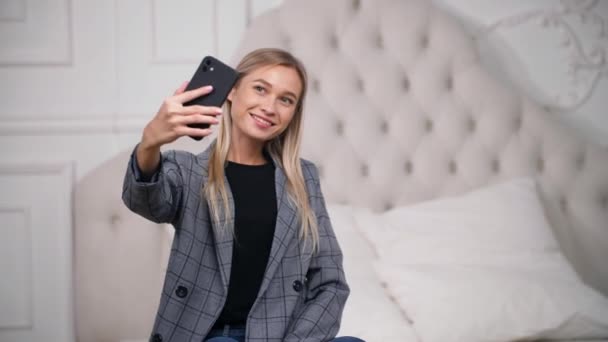 Attractive fille prend des photos ou enregistre des vidéos dans la chambre à coucher pour ses médias sociaux. — Video