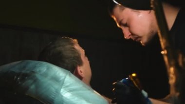 Dövme salonlarında dövme makinesiyle çalışan sanatçılar mürekkep boyası uyguluyor.