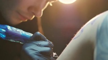 Önlem olarak eldiven takmış, çalışan dövme sanatçısının yakın çekimi..