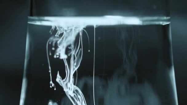 Warna putih tinta tetes, menetes aliran dalam air cair. Pewarna gading memercikkan percikan. — Stok Video