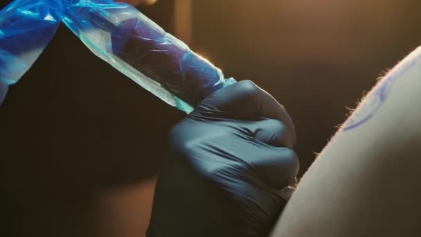 Närbild av arbetande tatueringsmaskin täckt av plastfolie för skydd. — Stockvideo
