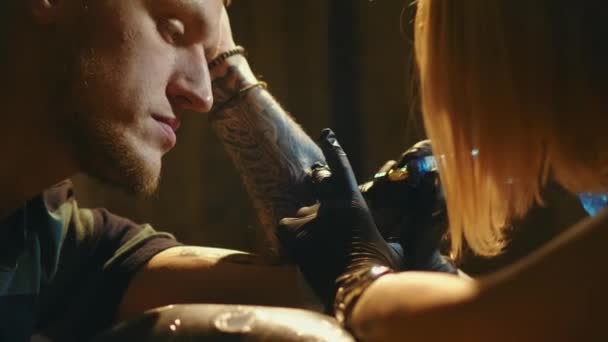 Kvinnlig tatuerare mästare på jobbet med manliga kunder underarm mönster. Tatueringsstudio — Stockvideo