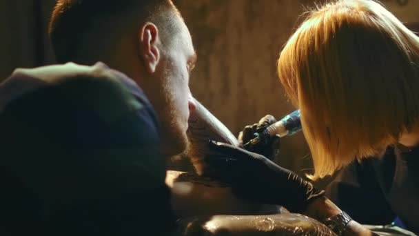 Жінка татуювання художник на роботі з чоловіком клієнтів руки. Чорні контури чорнила покриття . — стокове відео