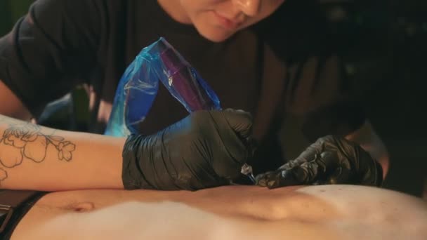Vrouwelijke tattoo artiesten werken met kale client borst, vult inkt met naald machine — Stockvideo