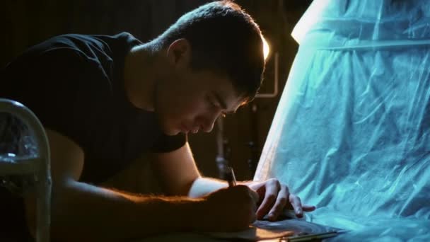 Close-up gezicht portret van mannelijke schilder met pen in de handen aan het werk met papier. — Stockvideo