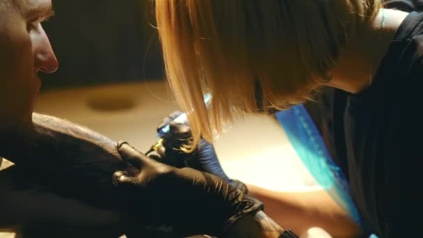 女纹身艺术家在工作与男人客户胳膊。黑色轮廓油墨覆盖. — 图库视频影像