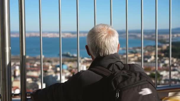 Le vieil homme aux cheveux gris se tient sur le pont d'observation du Christ Roi. Sites de Lisbonne. — Video
