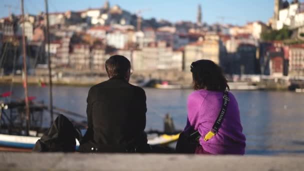 Paar reisender Touristen sitzt zusammen am Kai des Flusses Duero in Porto. — Stockvideo