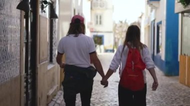Ericeira kasabasında el ele yürüyen aile turistleri..