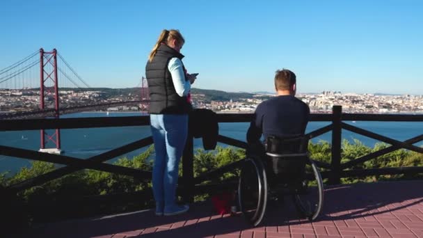 Tourist family with handicapped husband in wheelchair at Ponte 25 de Abril sight — Stock Video