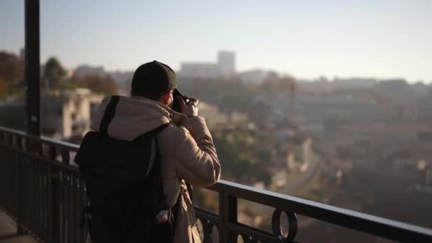 Photographe itinérant homme prend des photos avec un appareil photo tout en se tenant sur le pont. — Video