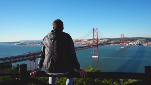 L'uomo turistico guarda Ponte 25 de Abril e il fiume Tago a Lisbona. — Video Stock