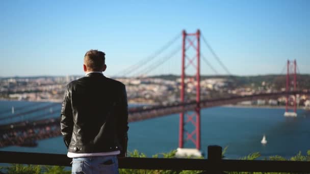 Reisender Mann im Urlaub beobachtet Stadtbild von Lissabon, Brücke 25 de Abril — Stockvideo