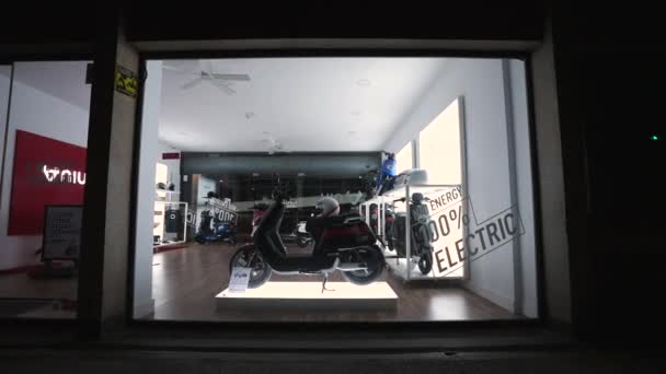 Ввечері дивись на електричний мотоцикл скутера через вітрину магазинів.. — стокове відео