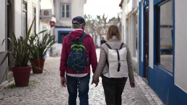 Γκρίζα μαλλιά της οικογένειας ζευγάρι των Αμερικανών τουριστών περπατά μαζί στην οδό Ericeira — Αρχείο Βίντεο