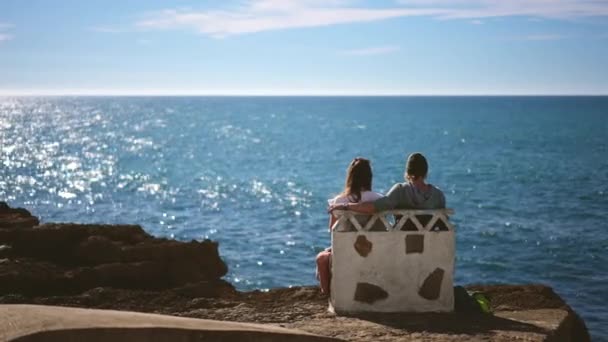游客夫妇坐在石头长椅上，安放在岩石上。海洋视觉放松 — 图库视频影像