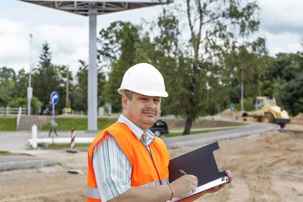 Ingeniero con carpeta cerca de los trabajos de reparación de carreteras — Foto de Stock