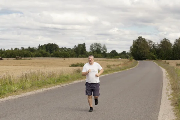 Gordo correndo em uma estrada rural — Fotografia de Stock