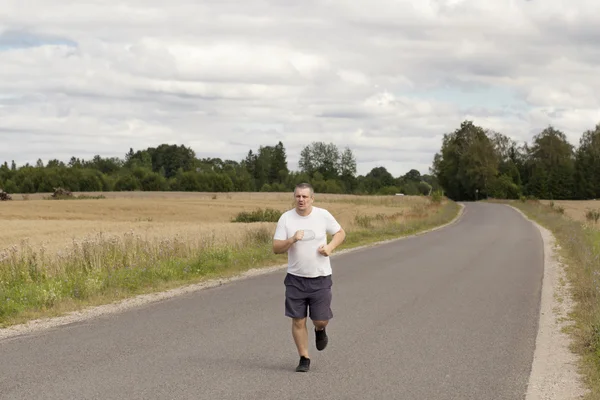 Gros homme courant sur une route rurale — Photo