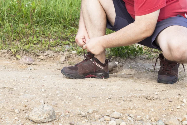 Hombre atado cordones de zapatos en el sendero —  Fotos de Stock