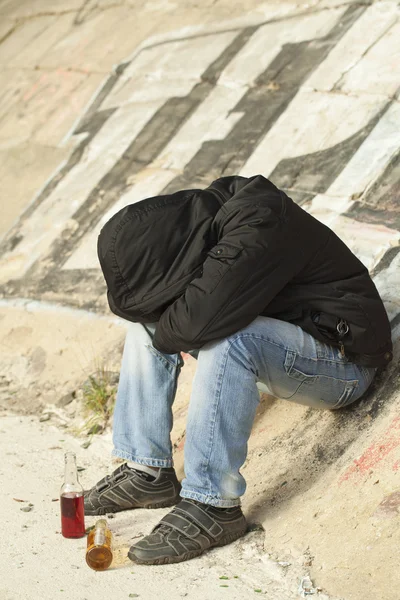 Niño durmiendo bajo un puente con dos botellas de bebida cerca —  Fotos de Stock