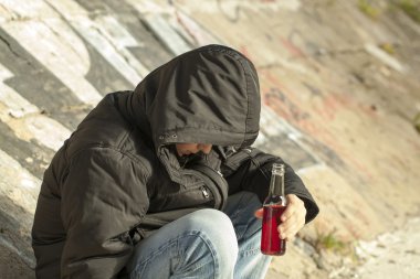 çocuk elinde bir şişe bir köprünün altında oturmak