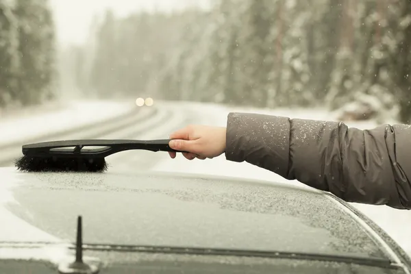 Limpiar el coche de la nieve en la tormenta de nieve en el camino — Foto de Stock