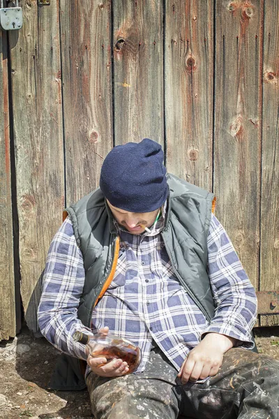 Бездомний, що спирається на двері сараю — стокове фото