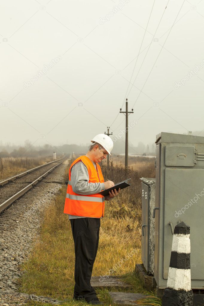 Railroad employee writes near the electrical enclosure