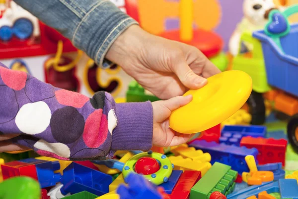 The mother and the child's arms at the toy pile — Stock Photo, Image