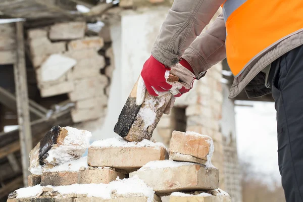 Pracownik zgłasza cegły w pobliżu spalony stary dom — Zdjęcie stockowe