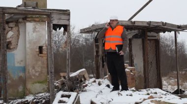 yanık eski evin yanında telefonda konuşurken mühendis