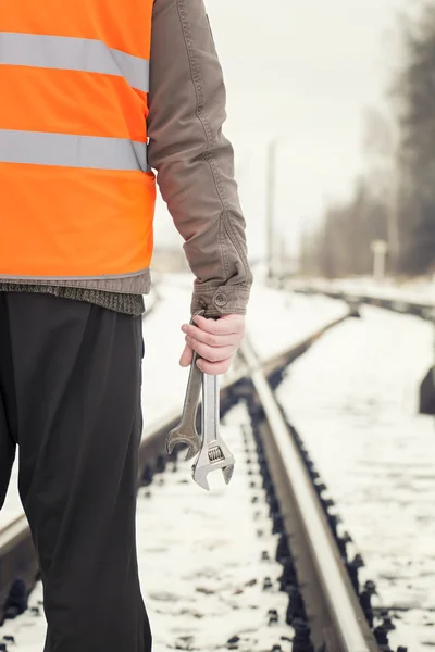 Werknemer met verstelbare sleutel in de handen op spoorweg kruisingen — Stockfoto