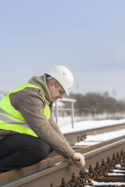 Spoorweg werknemer met verstelbare sleutel fix de moer — Stockfoto
