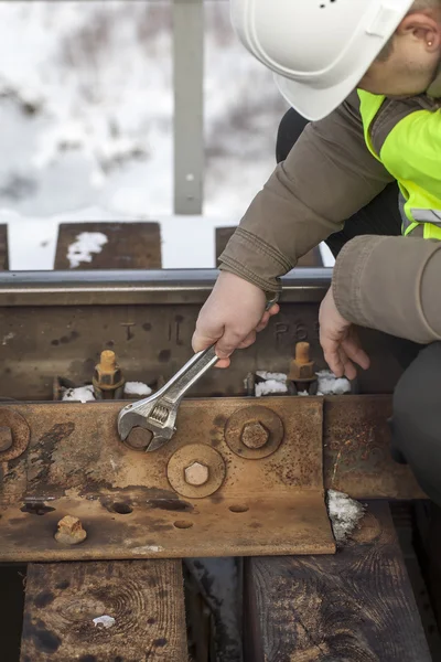Spoorweg werknemer met moersleutel fix de moer op de brug — Stockfoto