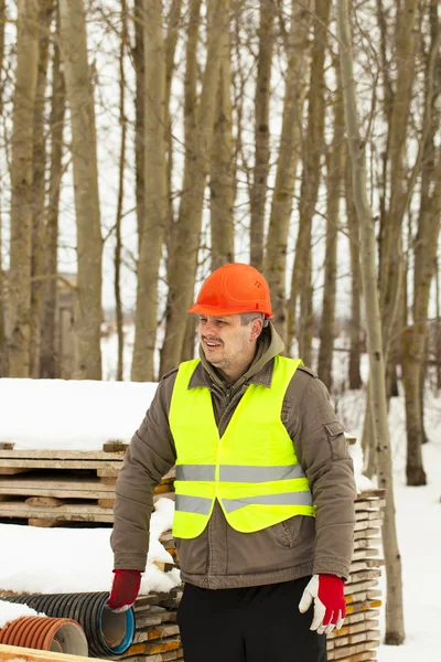 Bouwer in de buurt van de bouwmaterialen in de winter — Stockfoto
