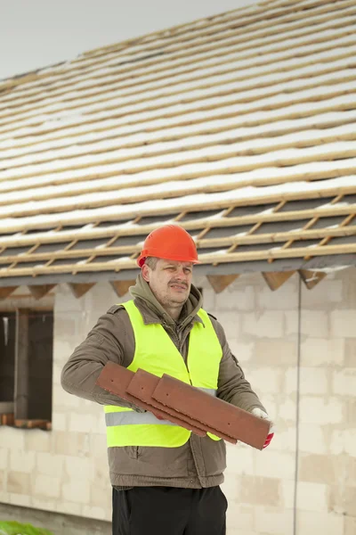 Builder z dachówek w pobliżu nowego budynku — Zdjęcie stockowe