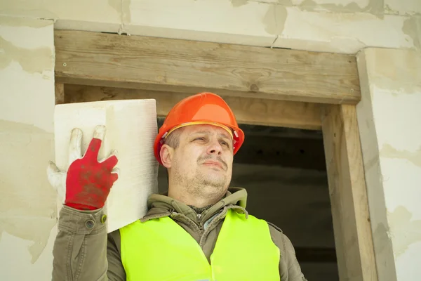 Builder with a concrete block on shoulder at new building — Stock Photo, Image