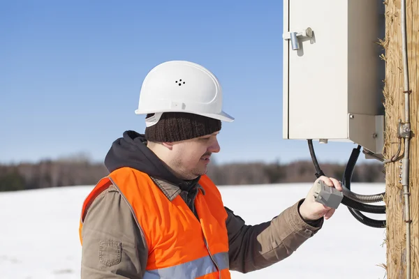 Elektriker mit Stromkabel in der Hand in der Nähe des Schaltschranks — Stockfoto