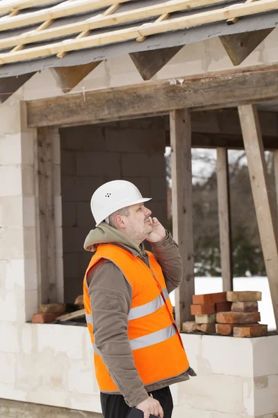 Construction manager talking on the cell phone near new building — Stock Photo, Image